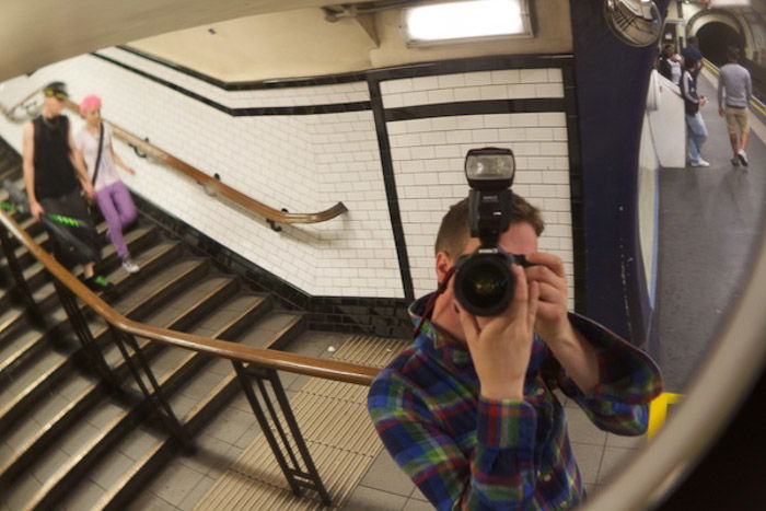 A photographer taking a self portrait in a subway station mirror, demonstrating use of dynamic tension in photography composition 