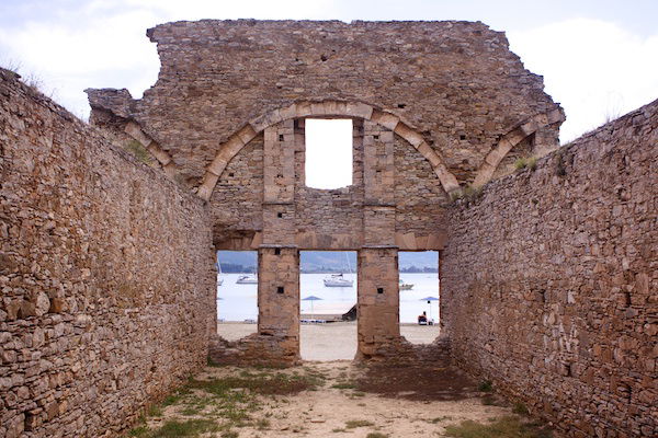 Abandoned stone ruins on a beach, with an arched entranceway. 