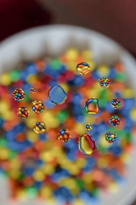 An image of water droplets with colorful m&m's behind -