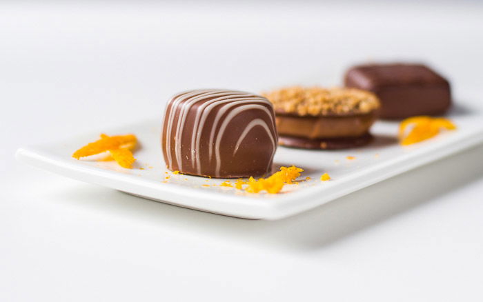 bright and airy still life photography of Belgian pralines decorated with orange peel.