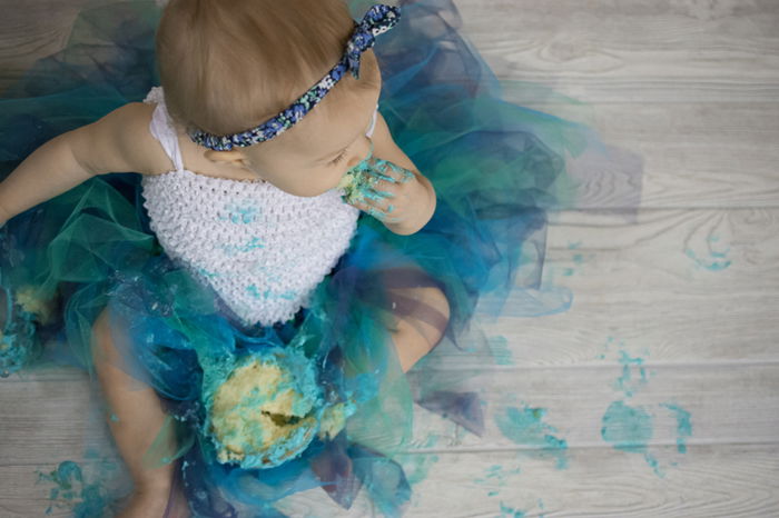 Cute overhead portrait of a baby messily eating a green cake