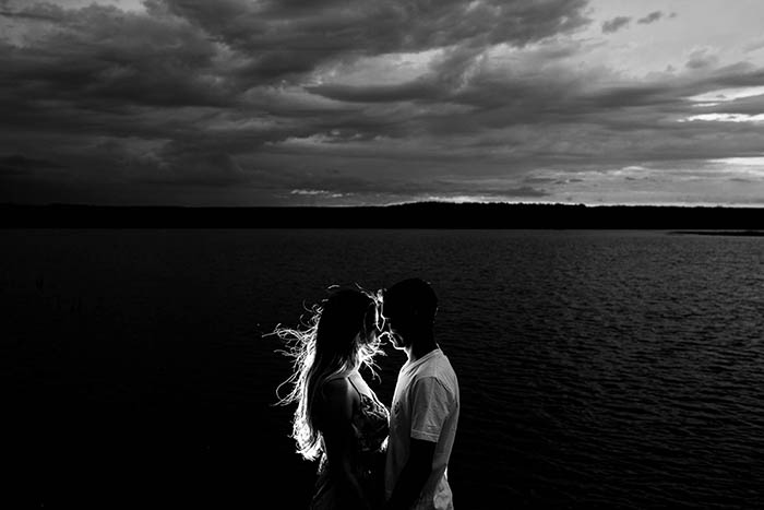 Black and white portrait photography of a couple with a view over the ocean in the background. 