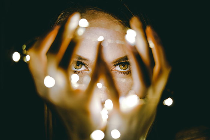 A girl poses for portrait photography with fairy lights out of focus 