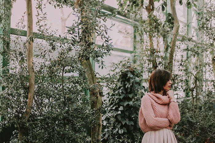 A female model posing for a portrait photography shoot in a greenhouse 