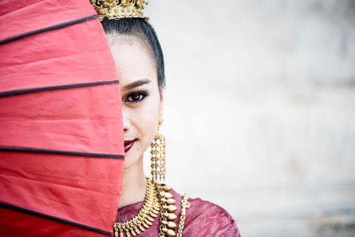 A beautiful female model poses behind a red umbrella 