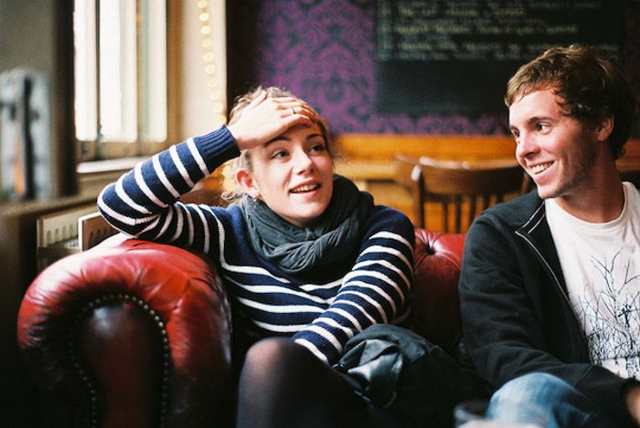 A candid portrait of two friends sitting on a sofa indoors