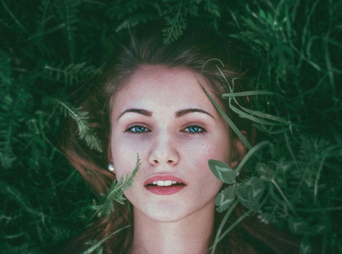 Portrait photo of a red-haired woman lying in the grass