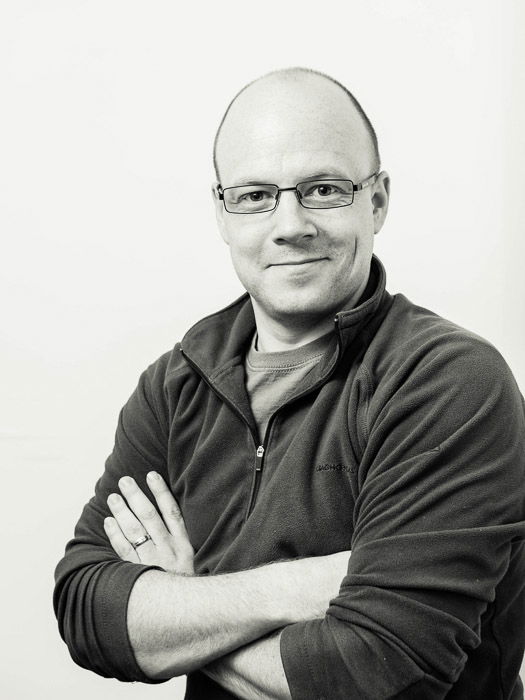 Black and white studio portrait of a man in glasses taken with loop lighting in studio