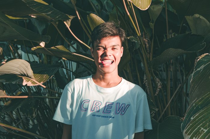 Candid shot of a boy infront of green leaves