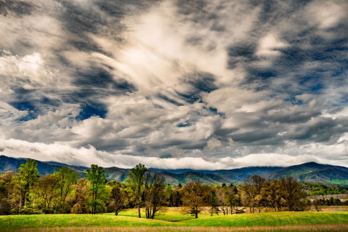 Dramatic Weather: Broad sky with multiple types of clouds over hills, fields, and forests