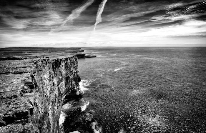 A black and white shot of a cliff overlooking water