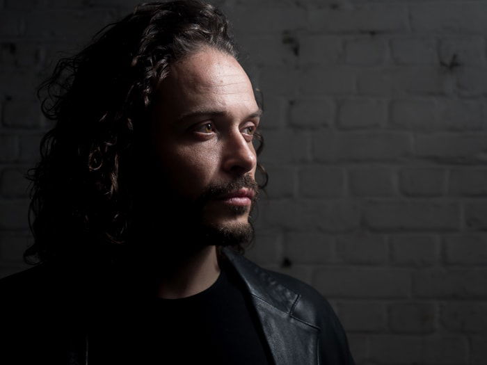 Low key portrait of a male model illustrating loop lighting with light modified by umbrella