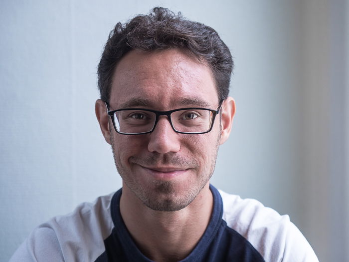 Portrait of man with glasses lit using split lighting with a reflector