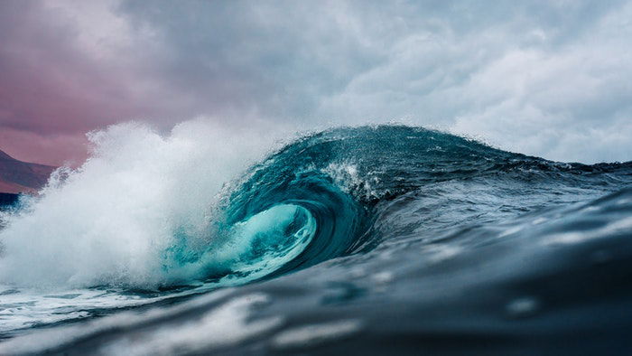 An ocean wave on a cloudy day crashing down as an example of the golden ratio in photography