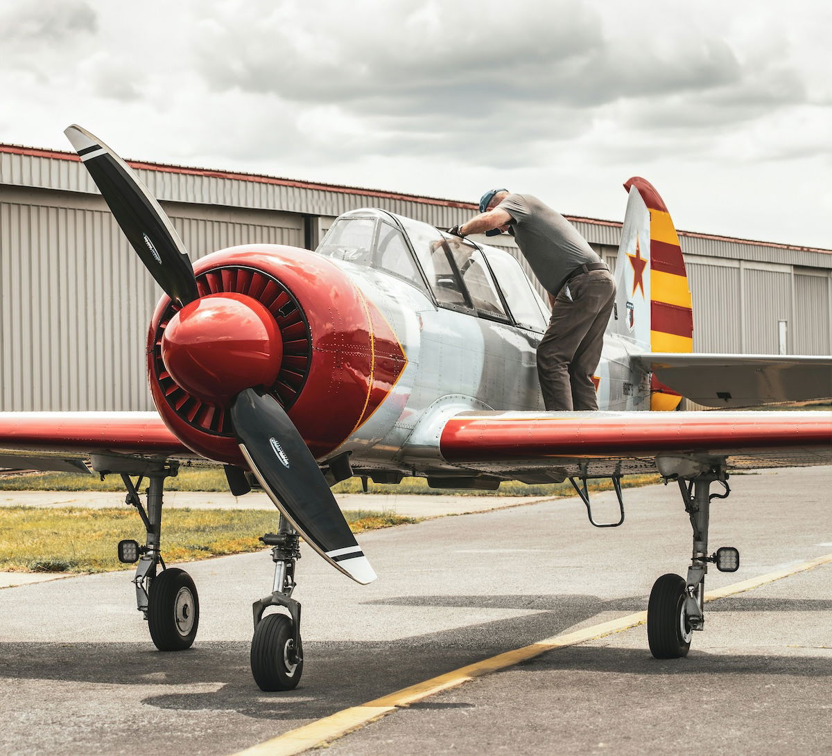 A person inspecting the inside of a parked Soviet Yak 52 fighter plane as an example of aviation photography