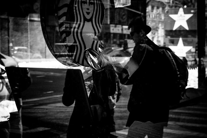 Black and white photograph of a Starbucks cafe with a couple overlaid on the customer inside. Double exposure effect reflection.