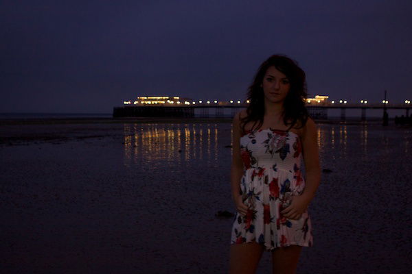 Portrait photography of a girl standing on a beach. Twilight photography.