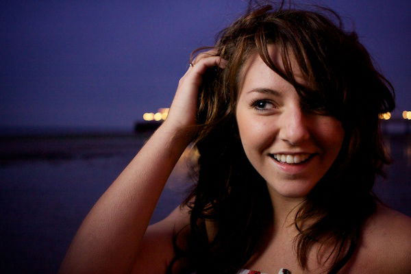 Close up portrait photography of a girl with her hands in her hair on a beach. Twilight photography.