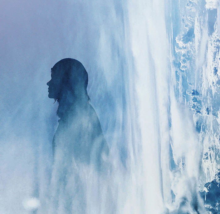 A silhouette of a woman double exposed with an image of clouds