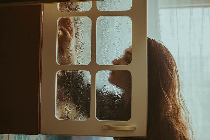 picture taken through a cabinet door of a young woman. Self portrait photography