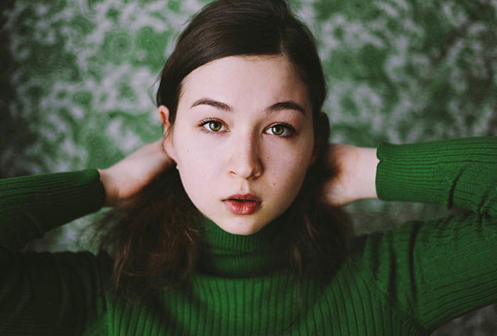 A girl poses for self portrait photography emphasising the use of only one color, green