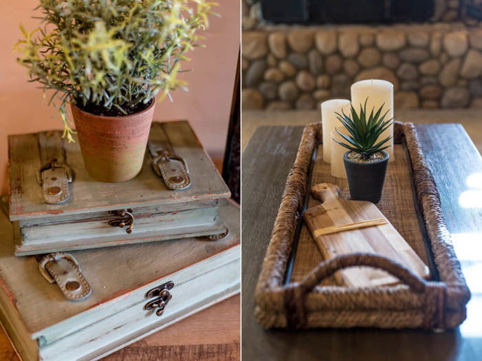 real estate photo of decor with a flowerpot on top of some books and a wooden tray with candles