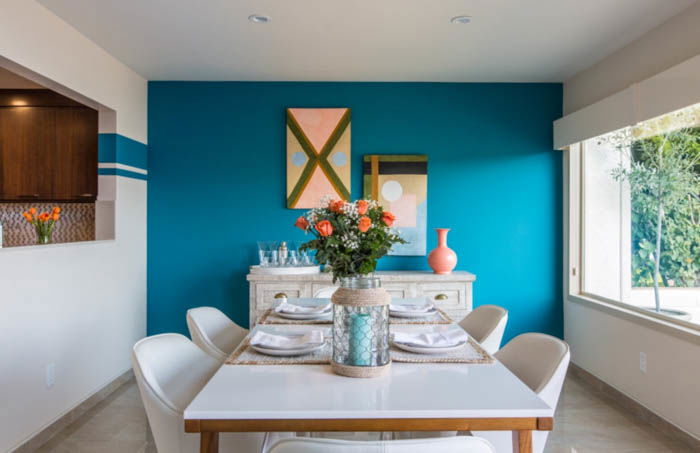 sunny dining room with white furniture and a blue wall in the background