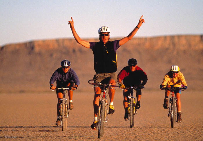 four men bicycling in a desert