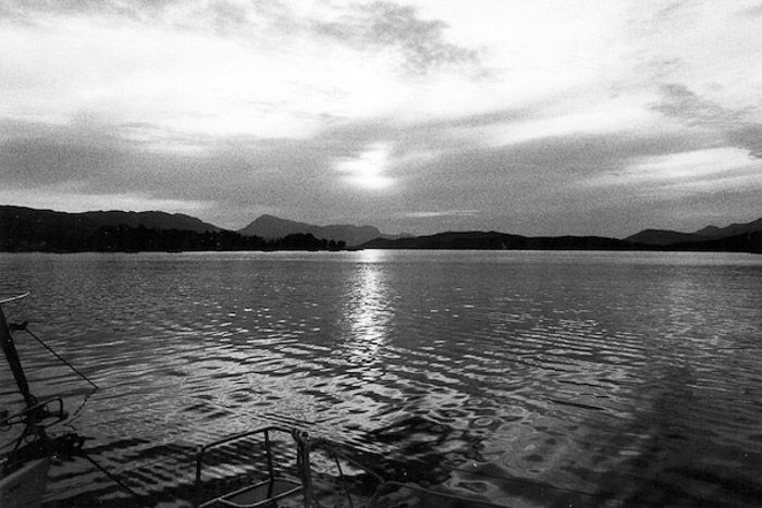 A serene shot of a lake with mountains in the background shot on black and white film