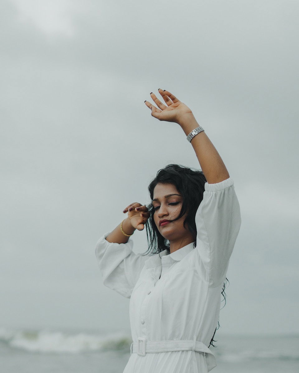 A woman in a white dress posing with her arm up