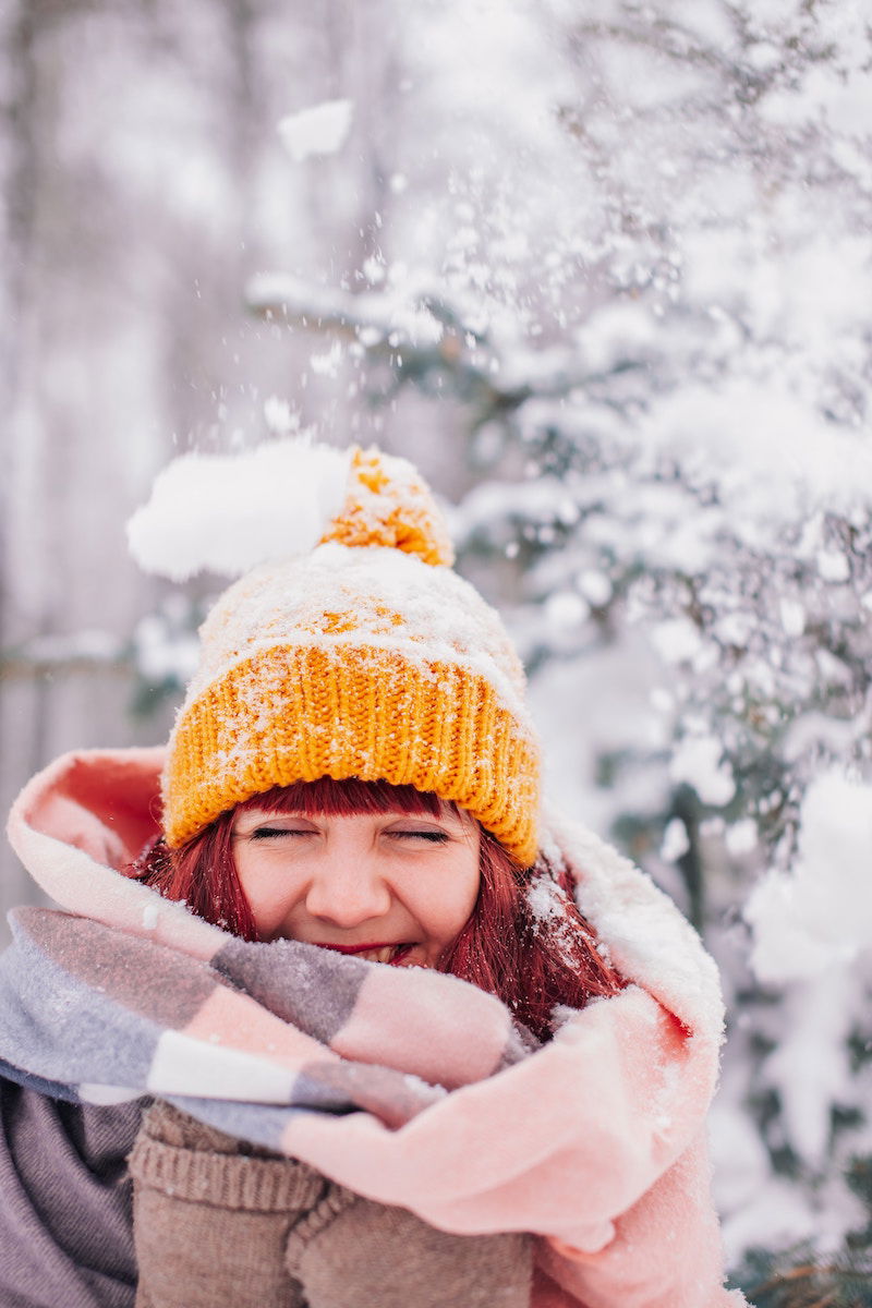 A woman with a winter hat and scarf with her eyes closed