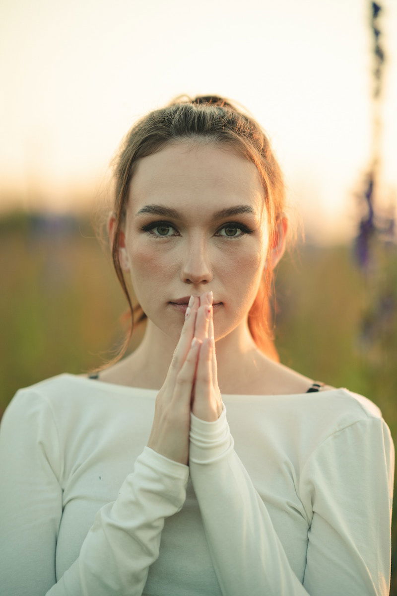 Woman with her hands pressed together and up to her mouth