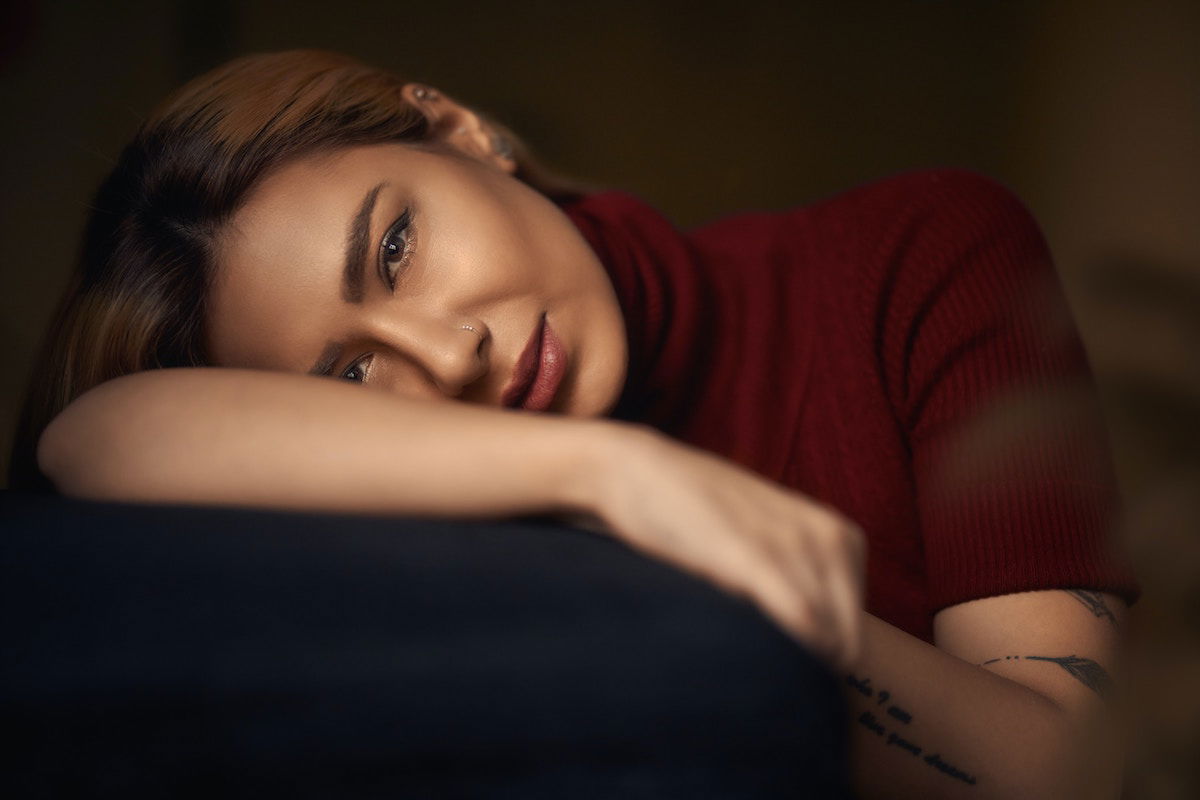 A woman with her head resting on her arm with her head titled as an example of a female pose