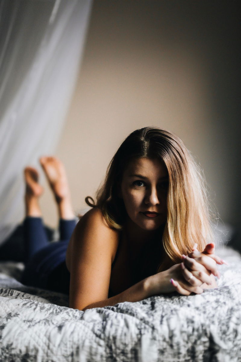 A woman lying on her stomach on a bed with her feet raised