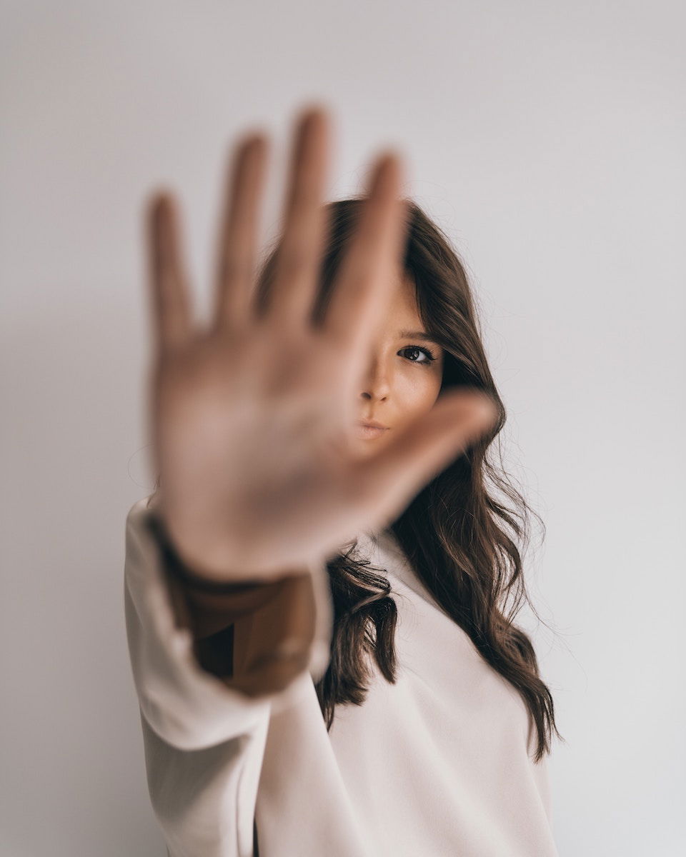 Woman with her palm up to the camera partially hiding her face