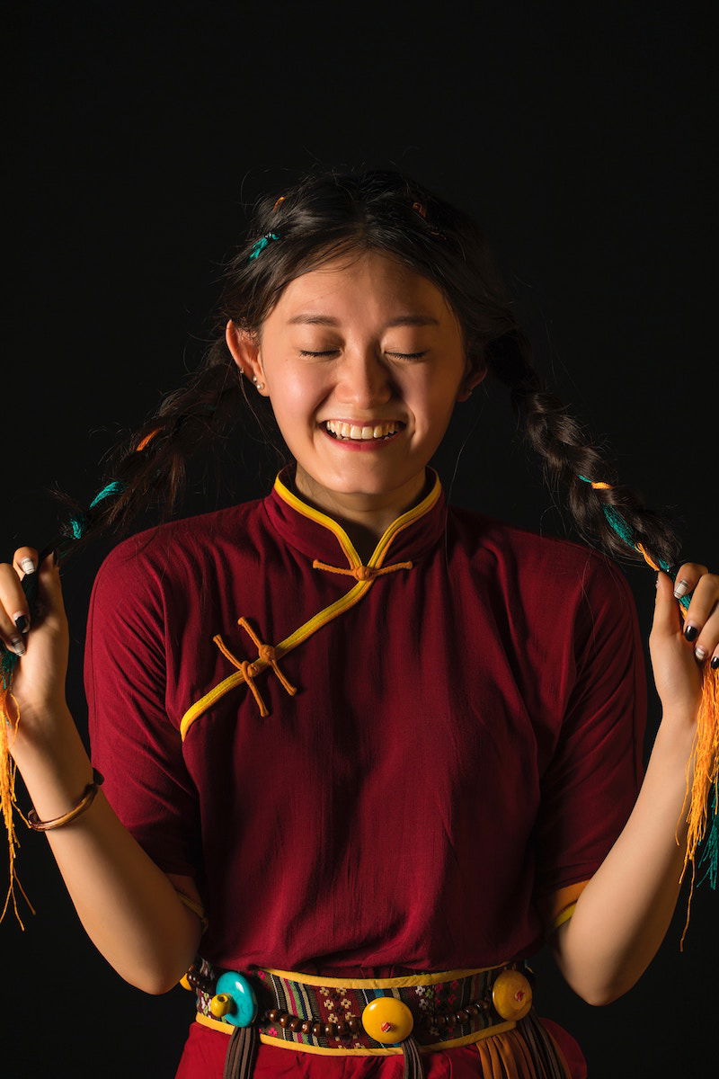 A woman smiling and pulling her pigtails with her eyes closed