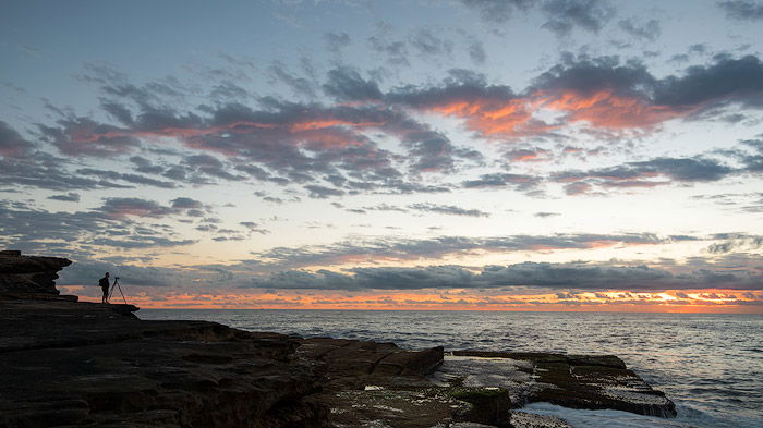 photographer taking a sunrise photo by the sea