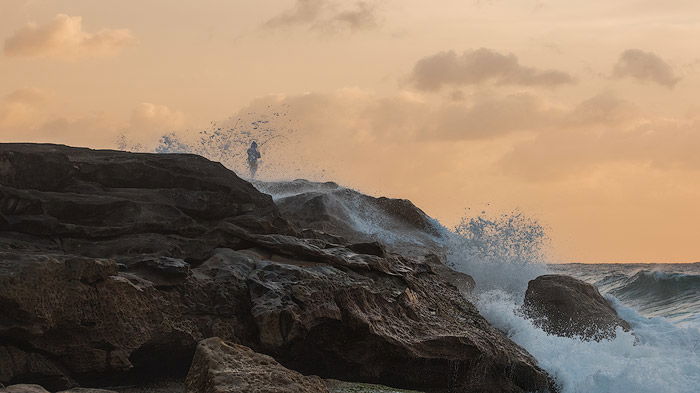 Seascape Photography of a man rocking fishing by the coast