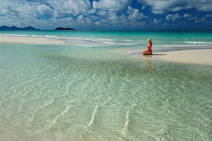 A girl kneels on a beach seascape in daytime