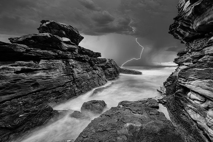 Lightning striking over a rocky seascape 