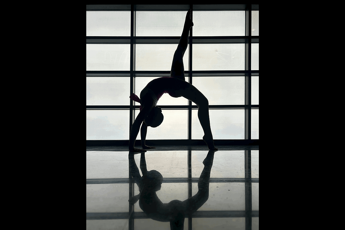 A yogini doing a back bend against a window creating a silhouette as an example of creative yoga photography