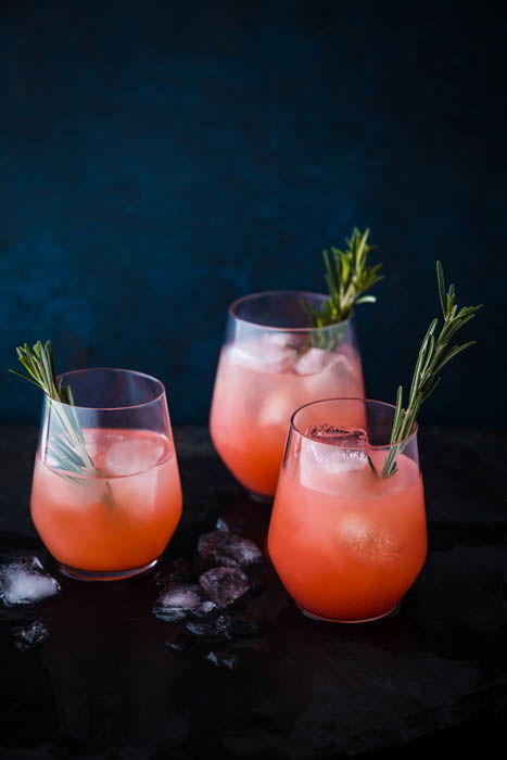 Atmospheric food photography shot of three orange cocktails on rustic background