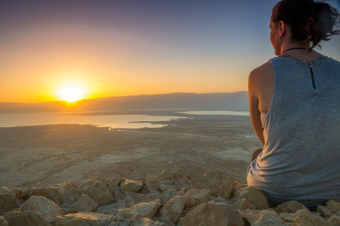 A woman watching the sunset in calm coastal location during the golden hour