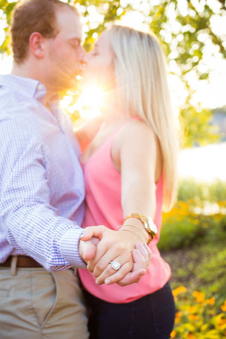 engagement photography of a kissing couple, with attention drawn to the ring - photo was taken using reflectors for lighting