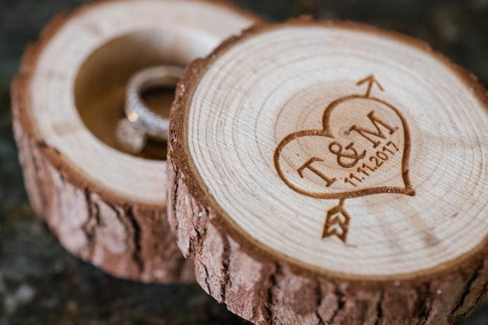 An engagement ring box made out of wood with a heart and arrow with the bride and groom's initials