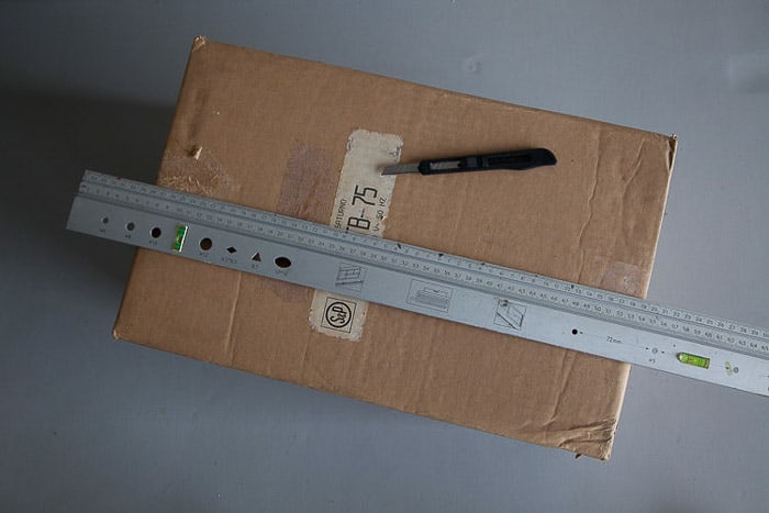 Overhead shot of a box, steel ruler and knife—tools you need to make a light box