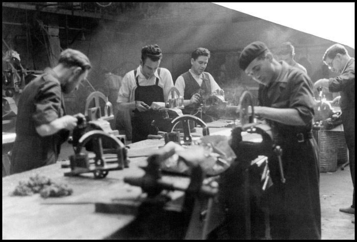 Black and white photo of men at work in a factory by Gerda Taro