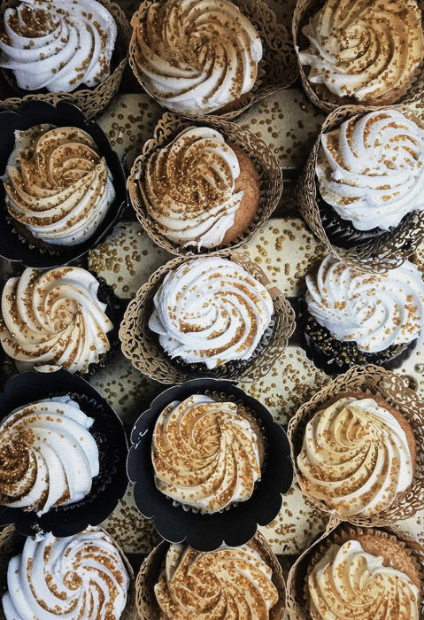 A bunch of cupcakes decorated with swirls of frosting and topped with sprinkles.