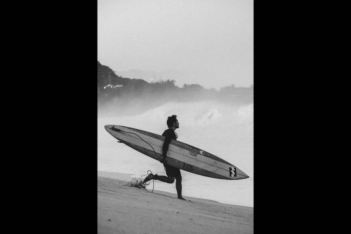 A surfer running on a beach as an example for sports photography