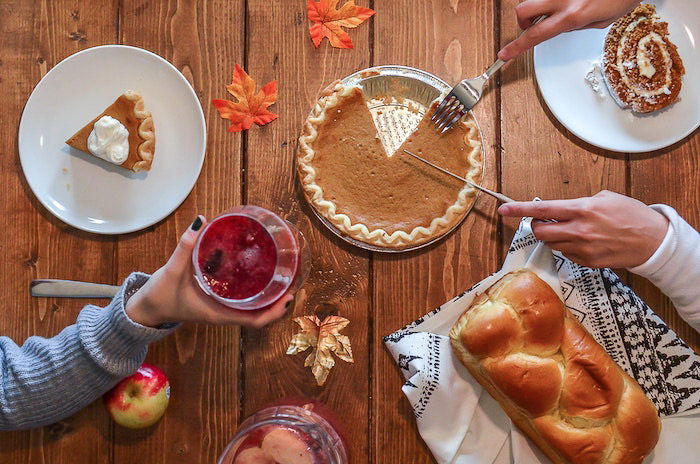 A table set with Thanksgiving dinner foods, including pie and a drink. 